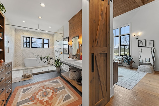 full bathroom featuring hardwood / wood-style flooring, recessed lighting, vanity, a freestanding tub, and walk in shower