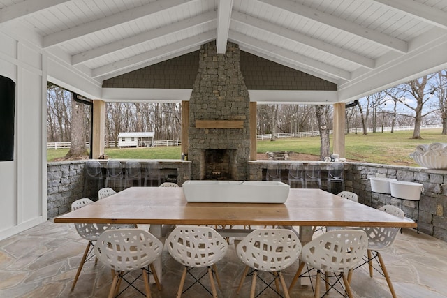 view of patio / terrace featuring outdoor dining space, an outdoor stone fireplace, and fence