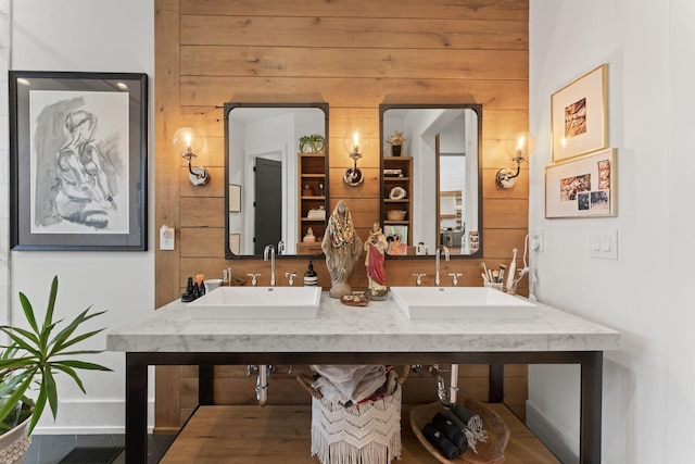 bathroom featuring wood walls and a sink