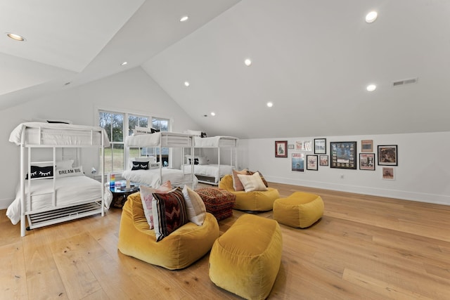 living area featuring lofted ceiling, light wood-type flooring, visible vents, and baseboards