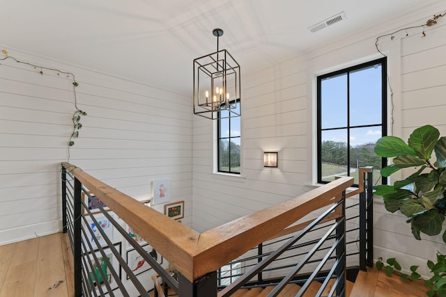 stairs with a chandelier, wood finished floors, and visible vents