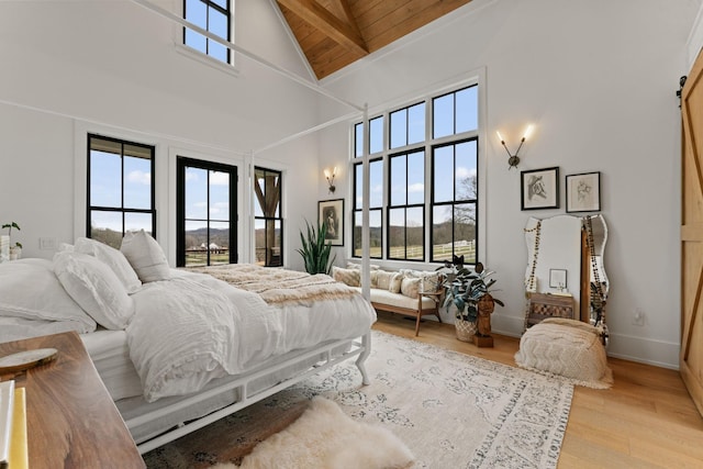 bedroom with light wood-style floors, multiple windows, beamed ceiling, and baseboards