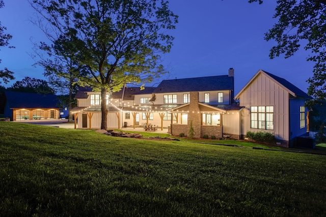 back of property with a patio area, a chimney, a lawn, and board and batten siding