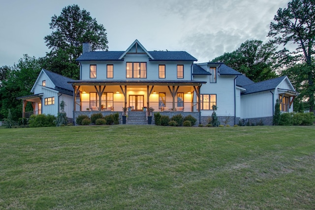 rear view of property featuring covered porch, roof with shingles, a chimney, and a lawn