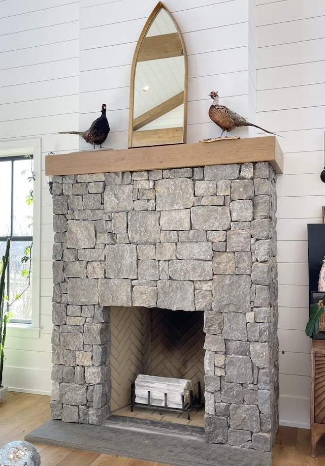 room details with a fireplace, wood walls, and wood finished floors