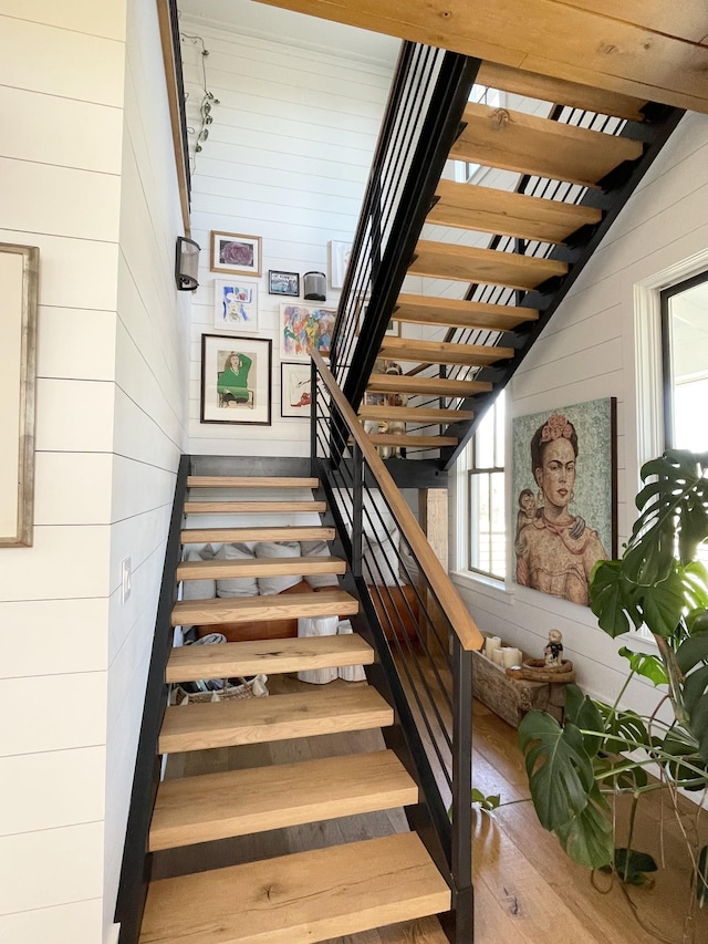 staircase with wooden walls and wood finished floors