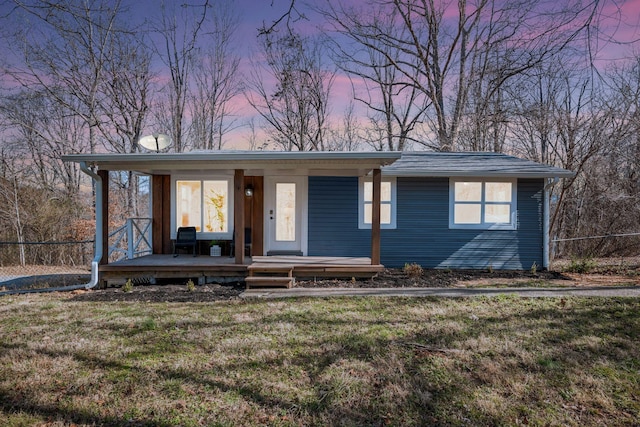 view of front of property featuring a porch, fence, and a lawn