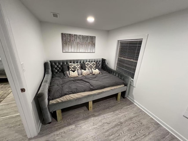 bedroom with visible vents, baseboards, and wood finished floors