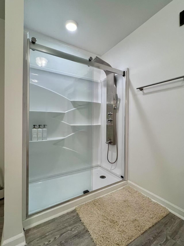 bathroom with a shower stall and wood finished floors