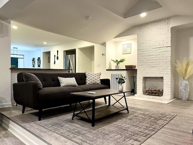 living room with lofted ceiling, recessed lighting, wood finished floors, visible vents, and a brick fireplace