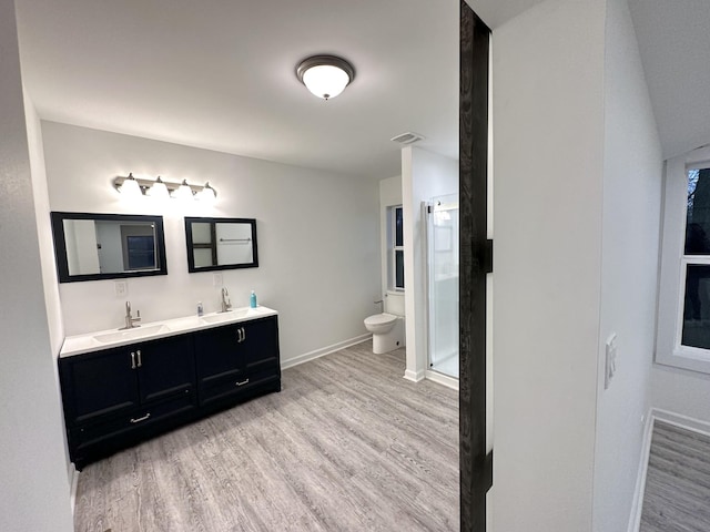 full bathroom with toilet, a stall shower, a sink, and wood finished floors