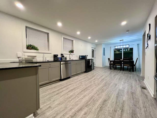 kitchen featuring dark countertops, light wood finished floors, gray cabinets, and stainless steel dishwasher