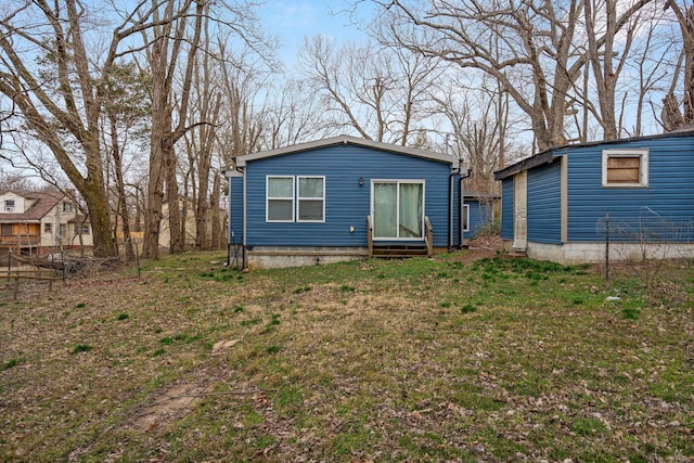 rear view of property featuring entry steps and a yard