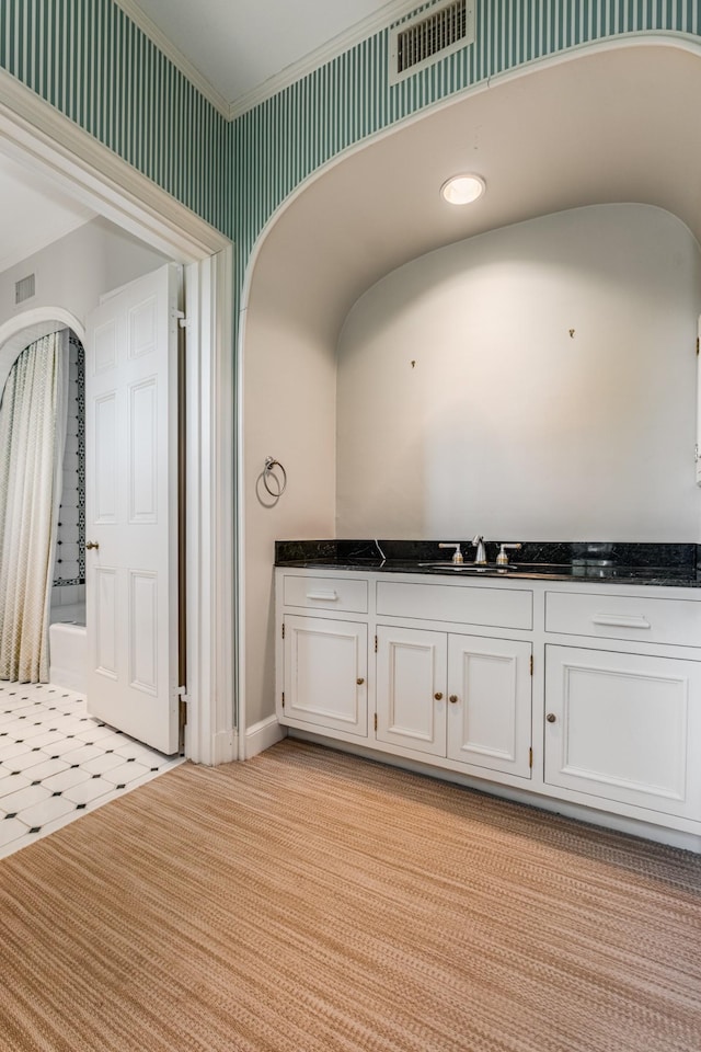 interior space featuring light carpet, wallpapered walls, visible vents, and ornamental molding