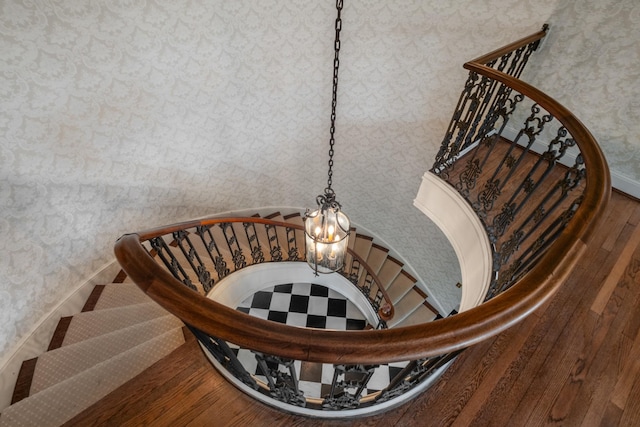 stairway with wallpapered walls, baseboards, and wood finished floors