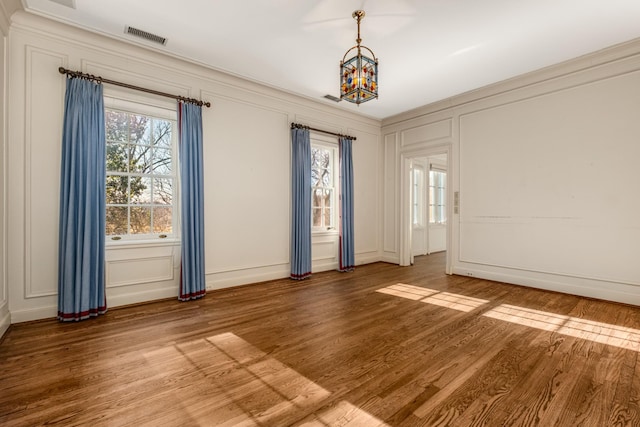 spare room with visible vents, a decorative wall, wood finished floors, and ornamental molding