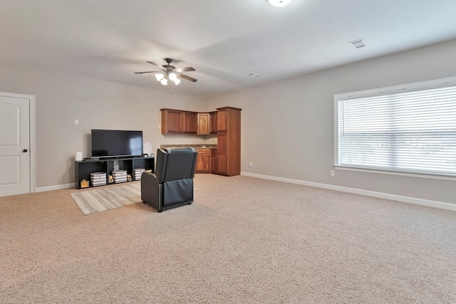 living area featuring visible vents, baseboards, a ceiling fan, and light colored carpet