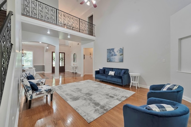 living room with arched walkways, stairway, wood finished floors, and baseboards