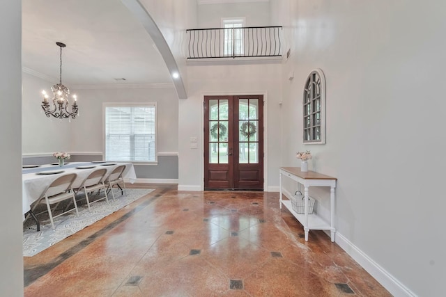 foyer with an inviting chandelier, baseboards, ornamental molding, and french doors