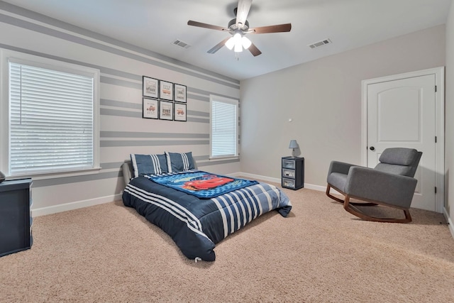 carpeted bedroom featuring ceiling fan, multiple windows, visible vents, and baseboards