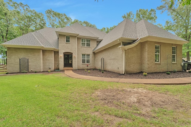 view of front facade with roof with shingles and a front lawn