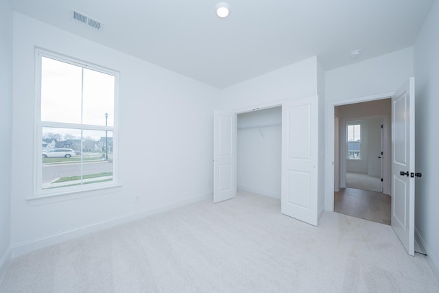 unfurnished bedroom with light colored carpet, a closet, visible vents, and baseboards