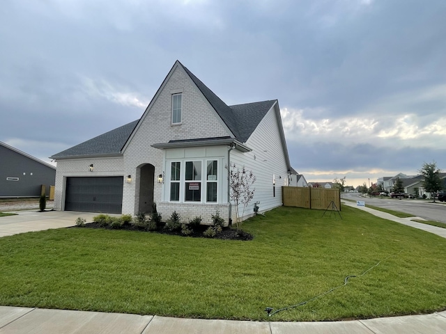 view of front of house with brick siding, a shingled roof, concrete driveway, an attached garage, and a front lawn