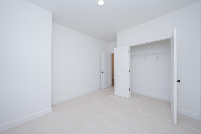 unfurnished bedroom featuring baseboards, a closet, and light colored carpet