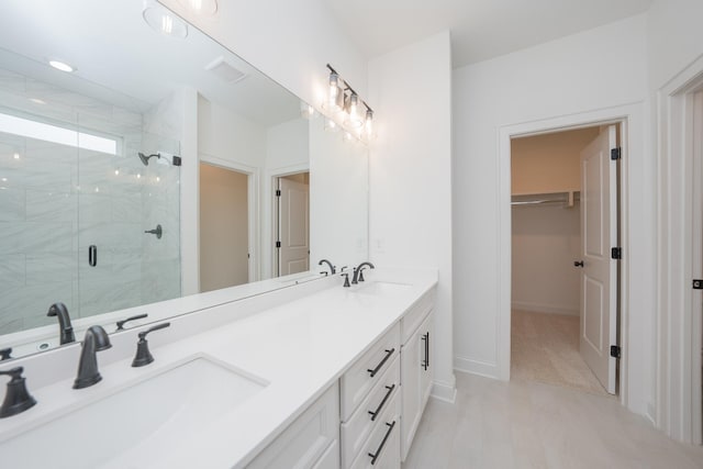 full bath featuring double vanity, a shower stall, a walk in closet, and a sink