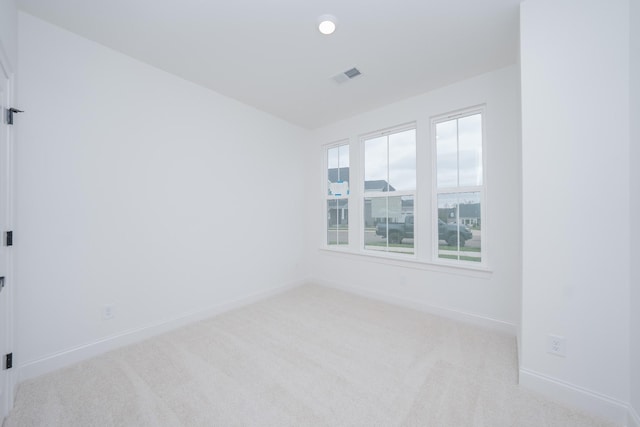 empty room with carpet, visible vents, and baseboards