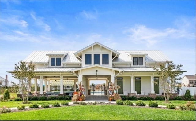 rear view of property with a porch, a standing seam roof, a yard, and metal roof