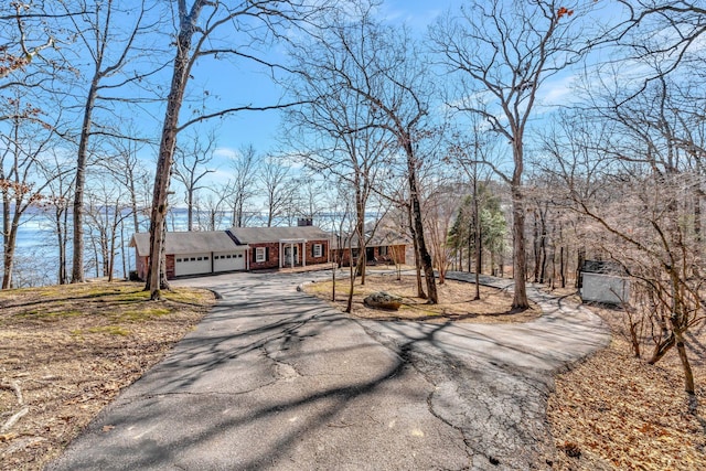 view of front of property with a garage, aphalt driveway, and a chimney