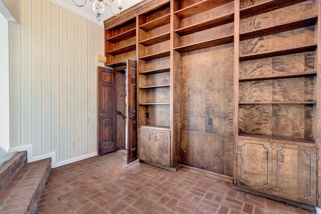 interior space featuring brick floor, an inviting chandelier, baseboards, and wallpapered walls