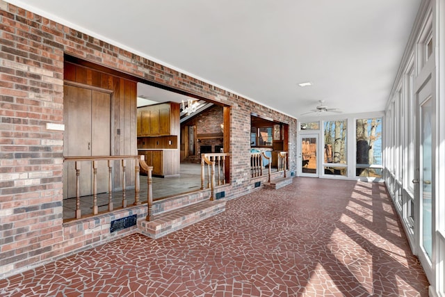 unfurnished sunroom with ceiling fan and a fireplace