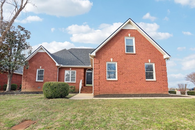 traditional home with a shingled roof, a front yard, crawl space, and brick siding