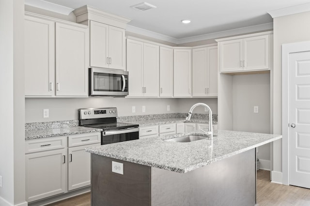 kitchen with visible vents, appliances with stainless steel finishes, a kitchen island with sink, a sink, and wood finished floors