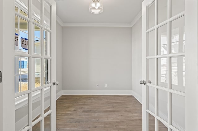 unfurnished room with baseboards, wood finished floors, and crown molding