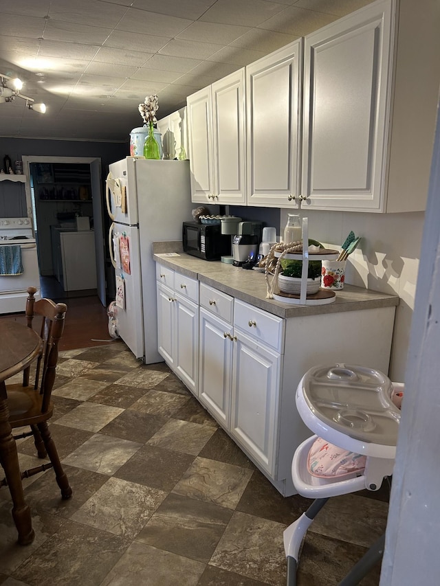 kitchen featuring light countertops, white appliances, washer / dryer, and white cabinets