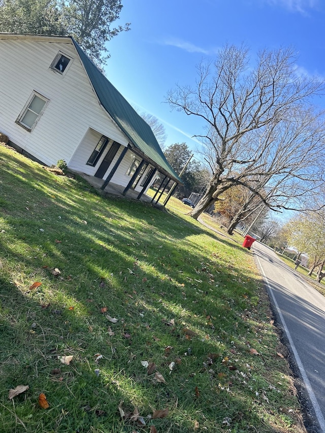 view of property exterior featuring metal roof and a yard