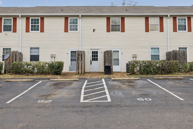 view of building exterior featuring uncovered parking and fence