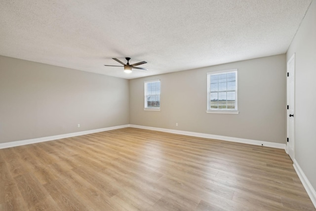 empty room with light wood-style flooring, baseboards, ceiling fan, and a textured ceiling