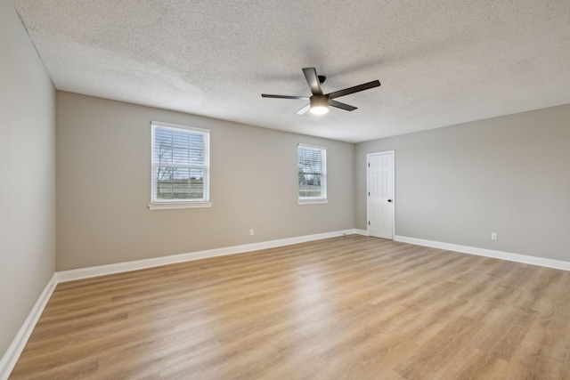 empty room with light wood-style floors, a textured ceiling, baseboards, and a ceiling fan