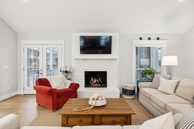 living area with lofted ceiling, a fireplace, wood finished floors, and baseboards