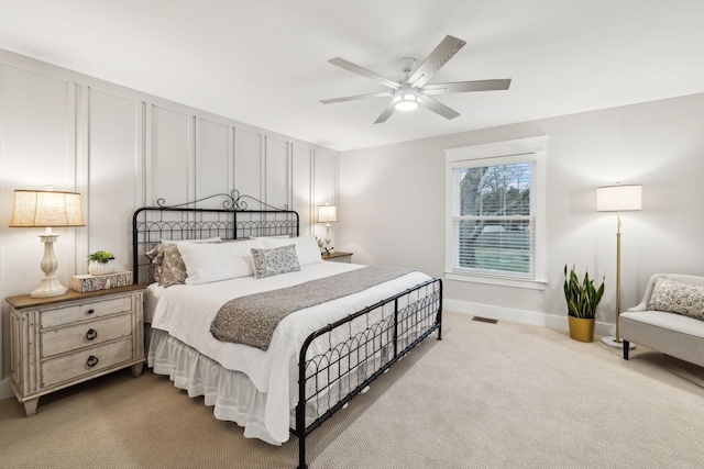 bedroom featuring visible vents, baseboards, ceiling fan, carpet floors, and a decorative wall