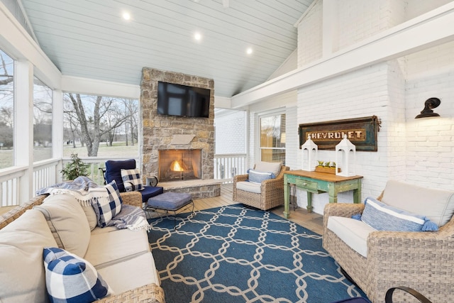 sunroom / solarium featuring lofted ceiling, wood ceiling, and an outdoor stone fireplace