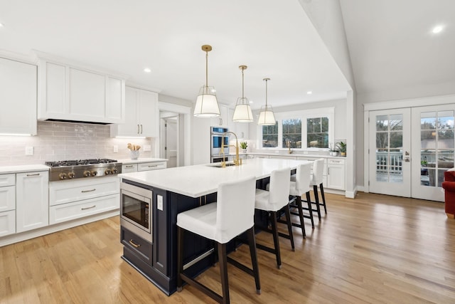 kitchen featuring appliances with stainless steel finishes, light countertops, a sink, and white cabinetry