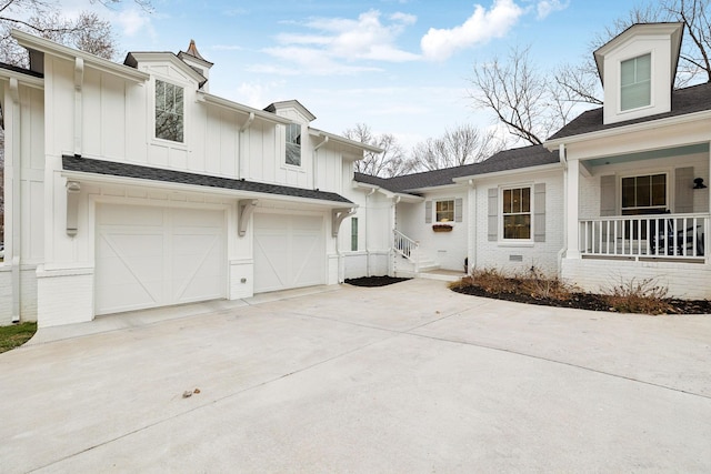 view of front of home with brick siding, concrete driveway, covered porch, board and batten siding, and a garage