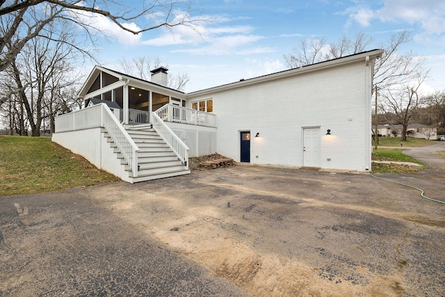 exterior space with brick siding, a chimney, and stairs