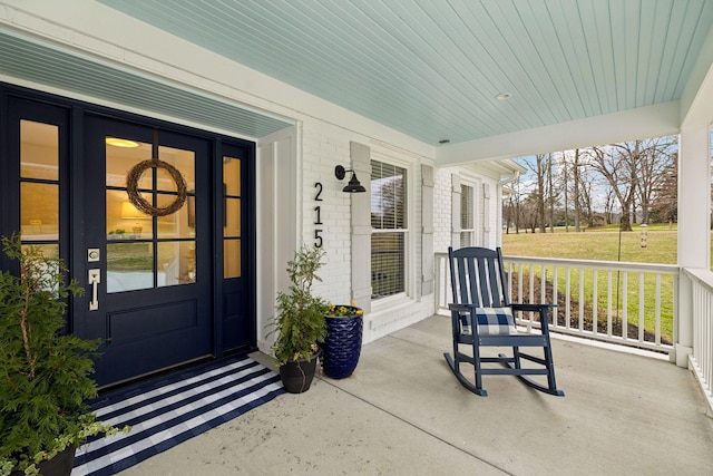 doorway to property featuring covered porch and brick siding