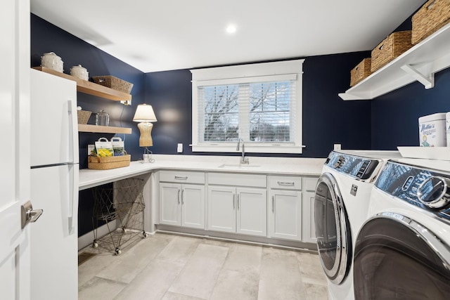 laundry room featuring cabinet space, a sink, and separate washer and dryer